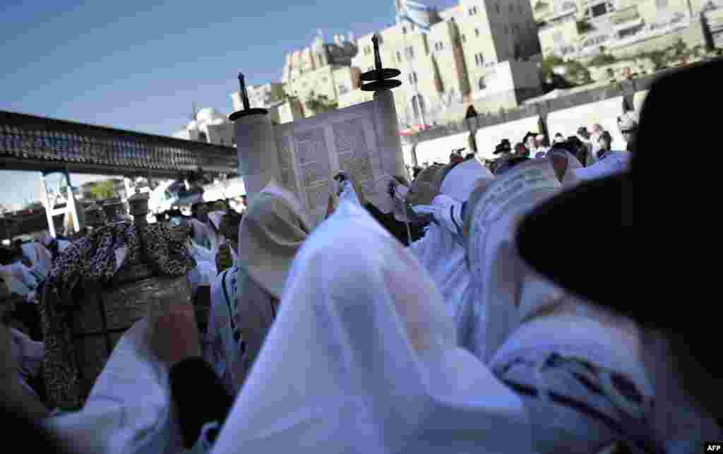 Jewish men draped in prayer shawls read from the Torah scrolls as they perform the Cohanim prayer (priest&#39;s blessing) during the Pesach (Passover) holiday at the Western Wall in the Old City of Jerusalem.