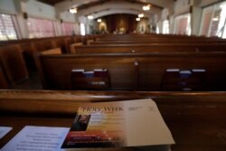 A leaflet listing Holy Week activities sits among empty pews during a live-streamed mass at the St. Augustine Church & Catholic Student Center, March 29, 2020, in Coral Gables, Fla.