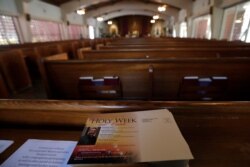 A leaflet listing Holy Week activities sits among empty pews during a live-streamed mass at the St. Augustine Church & Catholic Student Center, March 29, 2020, in Coral Gables, Fla.