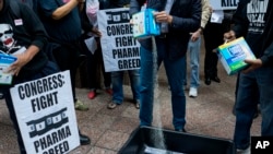 AIDS activists pour cat litter on an image of Turing Pharmaceuticals CEO Martin Shkreli in a makeshift cat litter pan during a protest highlighting pharmaceutical drug pricing, in front of the building that houses Turing's offices, in New York.