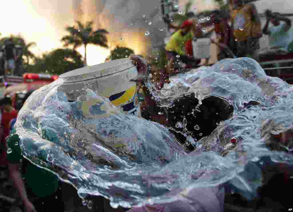 Water splashes out of the bucket of a resident as he and others help firemen in battling the blaze at a residential area in Mandaluyong, east of Manila, Philippines. &nbsp;