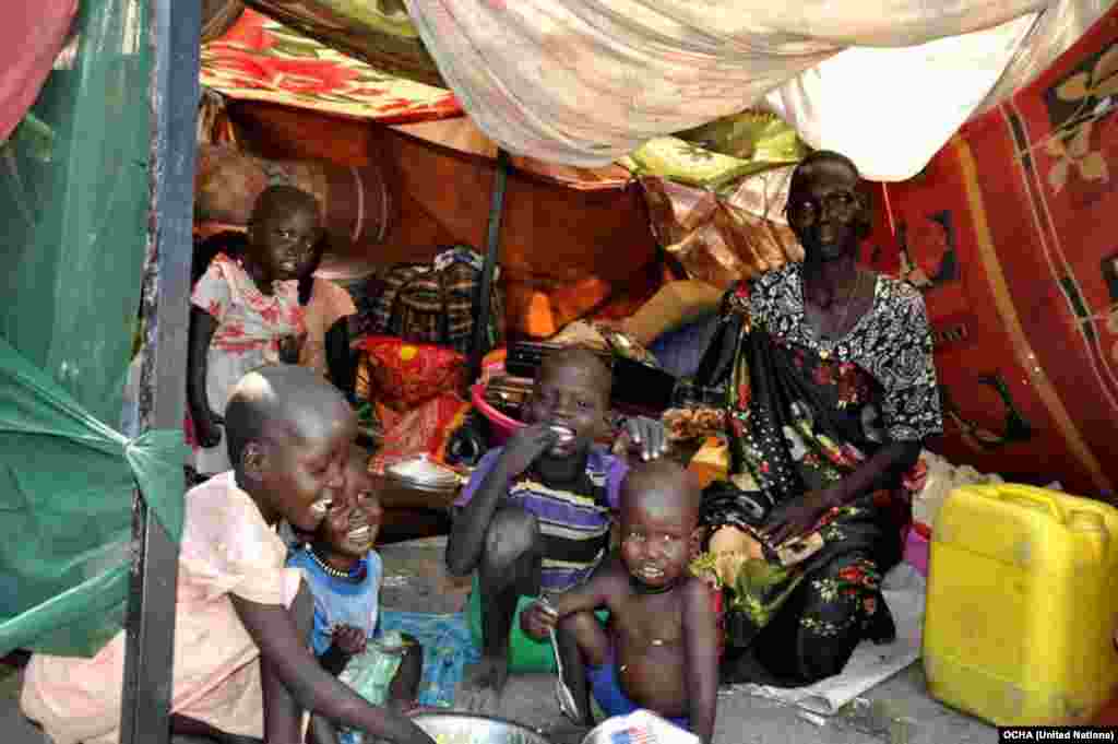 A woman and her children sit in their makeshift shelter at the U.N. compound in Malakal, where some 26,000 have sought shelter.