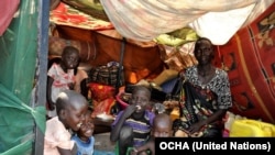 A woman and her children sit in their makeshift shelter at the U.N. compound in Malakal, where some 37,000 have sought shelter.