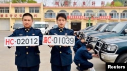 Officers of China's navy pose for photographs with the new (L) and old military car licence plates, in Qinhuangdao, Hebei province Apr. 28, 2013.