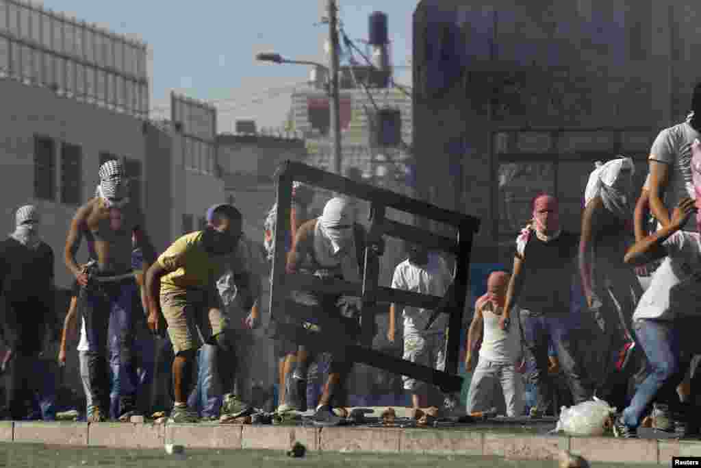 Palestinians hurl stones during clashes with Israeli police in Shuafat, an Arab suburb of Jerusalem, July 2, 2014. 