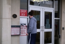 FILE - A person drops off their absentee ballot at a drop box at City Hall as early voting for the upcoming presidential election begins in Oshkosh, Wisconsin, Oct. 20, 2020.