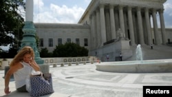 A woman uses her mobile phone at the plaza of the U.S. Supreme Court, Washington, June 25, 2014.
