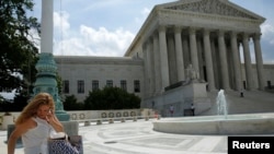 A woman uses her mobile phone at the plaza of the U.S. Supreme Court, Washington, June 25, 2014.