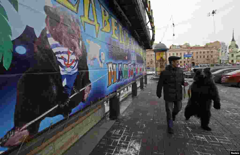 Alexander Ivanov, head of a traveling circus troupe based in Moscow, walks with three-year-old bear Dasha near an advertisement for their upcoming performance in St. Petersburg. The troupe will soon perform for the first time in 20 years in Russia&#39;s second city.