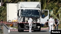 FILE - Investigators work near the heavy truck that ran into a crowd at high speed in Nice, France, July 15, 2016. A Maryland man allegedly inspired by that attack has been detained, the U.S. Justice Department said Monday. 