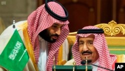 محمد بن سلمان، ولیعهد عربستان سعودی، در حال صحبت با پدرش، ملک سلمان، پادشاه سعودی، در نشست شورای همکاری خلیج فارس در رياض. آرشیو، ۹ دسامبر ۲۰۱۸