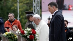 El papa Francisco y el presidente de Letonia, Raimonds Vejonis (derecha) rinden homenaje en el Monumento a la Libertad en Riga, Letonia, el lunes, 24 de septiembre de 2018.