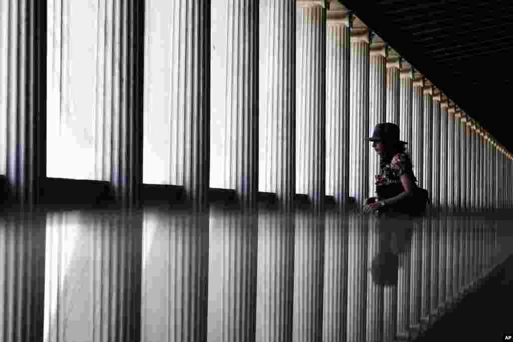 A tourist is reflected in a glass surface as she walks in the newly opened first floor of the Museum of the ancient Agora, Stoa of Attalos, central Athens, Greece. 