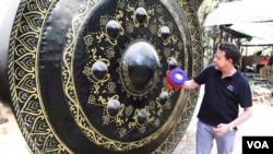 VOA correspondent Steve Herman tries his hand at ringing a giant gong. (Z. Aung/VOA)