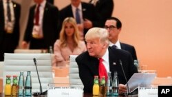 ປະທານາທິບໍດີສະຫະລັດ ທ່ານດໍໂນລ ທຣຳ ນັ່ງດ້ານໜ້າ ໃນຂະນະທີ່ທ່ານນາງ Ivanka Trump, ນັ່ງດ້ານຫຼັງ ເພື່ອເຂົ້າຮ່ວມກັບບັນດາຜູ້ຕາງໜ້າອື່ນໆໃນກອງປະຊຸມ ສຸດຍອດ G-20 ເຢຍຣະມັນ Hamburg, northern Germany, 8 ກໍລະກົດ 2017.