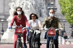 Cyclists, some wearing face masks, ride along The Mall near Buckingham Palace in central London, Britain, May 16, 2020, following an easing of coronavirus lockdown restrictions.