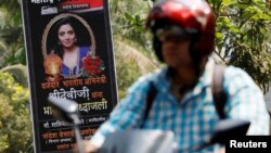 A man rides past a poster of Bollywood actor Sridevi outside her house in Mumbai, India, Feb. 27, 2018. The poster reads "To a quality Indian actress, Sridevi, we pay a heartfelt tribute."