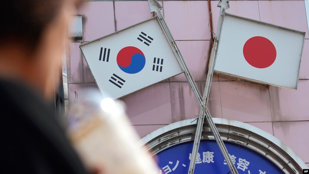 资料照：一名女子走过东京街头一家挂有日韩国旗的商店。（2019年8月2日）(photo:VOA)