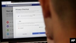 A man poses in front of a computer showing Facebook ad preferences pages in San Francisco, March 26, 2018. Facebook is giving its privacy tools a makeover as it reels from criticisms over its data practices and faces tighter European regulations in the coming months.