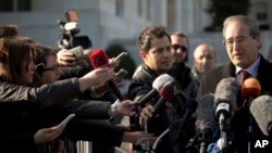 Journalists reach out to ask questions to Syrian Deputy Foreign Minister Faisal Makdad, right, during a short briefing to journalists after a meeting with the Syrian government at the United Nations headquarters in Geneva, Switzerland, Tuesday, Jan. 28, 2