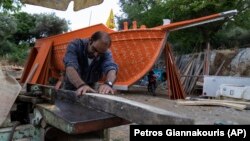 Giorgos Kiassos, one of the last remaining boatbuilders on Samos island, is shaping wood to be used on a traditional boat in the village Drakaioi on Thursday, June 10, 2021. (AP Photo/Petros Giannakouris)