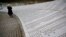 FILE - Fadila Efendic prays near memorial plaques at the Potocari genocide memorial center near Srebrenica, March 18, 2015. 