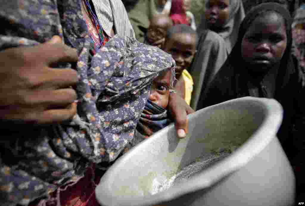 July 19: A woman carrying her baby queues for food in a camp established by the Somali Transitional Federal Government for the internally displaced people in Mogadishu. The United Nations said on Wednesday two regions of southern Somalia had been hit by t