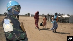 Women with children walk near a soldier of Darfur's joint U.N./African Union UNAMID peacekeeping force outside the UNAMID team site in Khor Abeche, 83 km (52 miles) northeast on Nyala (south Darfur), 10 Jan 2011