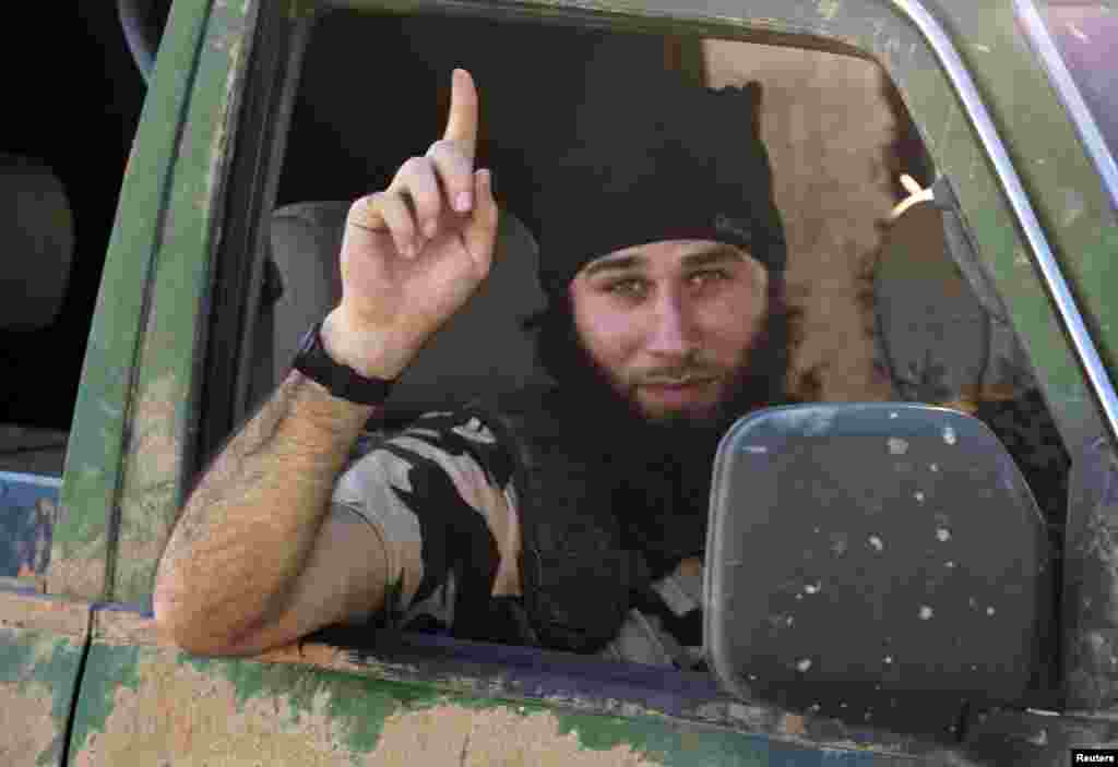 An Islamic State fighter gestures from a vehicle in the countryside of the Syrian Kurdish town of Kobani, Oct. 7, 2014.