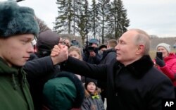 President Vladimir Putin shakes hands with a man after attending a wreath laying commemoration ceremony for the 77th anniversary since the Leningrad siege was lifted during World War II at the Piskaryovskoye Memorial Cemetery, Jan. 14, 2020.