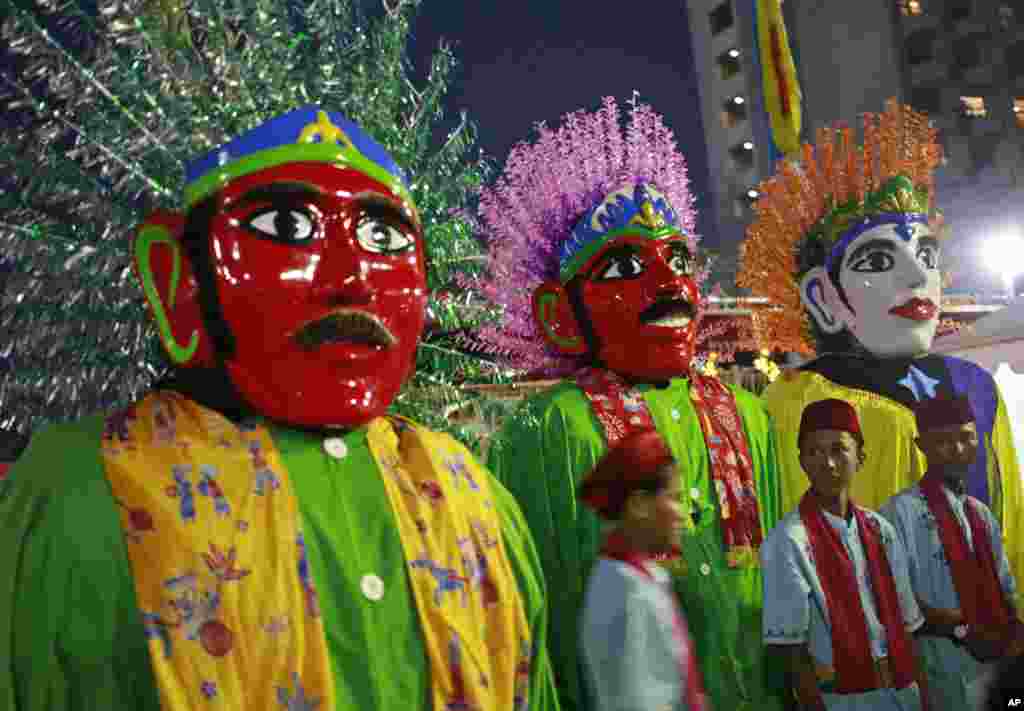 Indonesian youths stand near traditional giant effigies called &quot;ondel-ondel&quot; during a mass wedding held in celebration of the New Year in Jakarta, Indonesia, Sunday, Dec. 31, 2017. (AP Photo/Dita Alangkara)