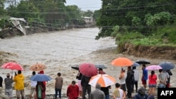 People look at a flooded creek near San Pedro Sula, Honduras, on Nov. 16, 2024.