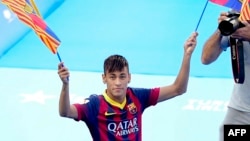 Le Brésilien Neymar da Silva Santos Junior, nouveau joueur du FC Barcelone, brandit deux drapeaux de son nouveau club lors de sa présentation au stade Camp Nou à Barcelone, le 3 juin 2013.