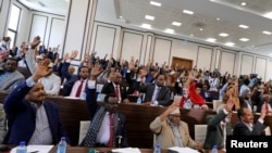 Somali parliament members raise their hands to approve the appointment of new Prime Minister Mohamed Hussein Roble, in Mogadishu, Sept. 23, 2020.