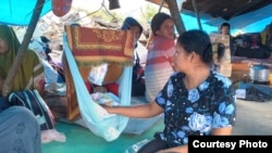 Seorang Ibu yang sedang menidurkan anaknya di ayunan di dalam tenda darurat di lokasi pengungsian warga desa Meli, Kecamatan Baebunta, Luwu Utara, Sulawesi Selatan, 16 Juli 2020. (Foto: Zwaib Leibe/SAR Mapala Muhammadiyah Indonesia)