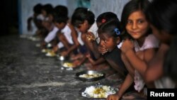 Murid-murid menikmati makan siang gratis di sebuah sekolah di desa di Bihar, India (19/7). Makanan yang terkontaminasi pestisidamerenggut 23 nyawa murid di sekolah itu.