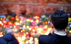 Seorang anggota komunitas Yahudi Halle menatap lilin yang menyala di luar sinagoga di Halle, Jerman 11 Oktober 2019, setelah dua orang tewas dalam penembakan. (Foto: REUTERS/Hannibal Hanschke)