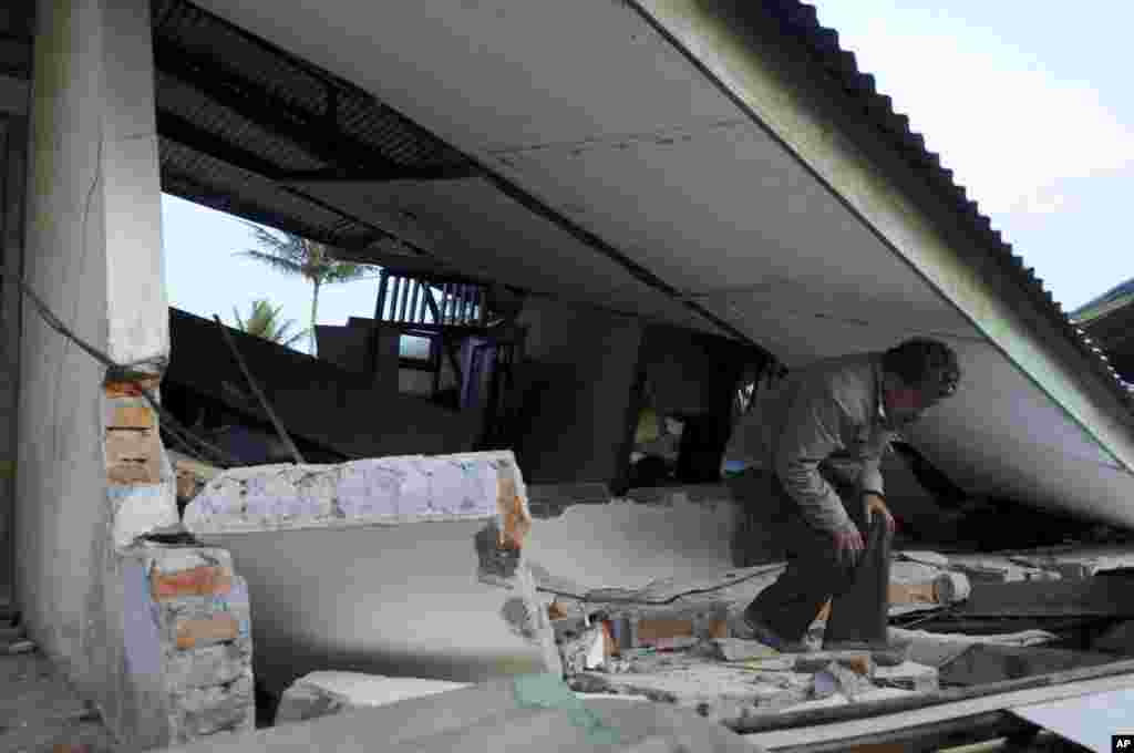 An Acehnese man makes his way under the collapsed roof of a building after it was destroyed by an earthquake in Ketol, Central Aceh, July 3, 2013. 