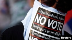 Seorang demonstran anti-pemerintah Thailand mengenakan masker bertuliskan "No Vote" saat melakukan pawai protes di Bangkok (31/1).