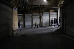 People walk next to closed shops of Tehran Bazaar following the tightening of restrictions to curb the surge of COVID-19 cases, Tehran, Apr. 10, 2021. (Majid Asgaripour/(West Asia News Agency via Reuters)