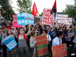 FILE - Protesters hold up signs in protest of a visit by Republican presidential candidate Donald Trump in Eugene, Oregon, May 6, 2016.