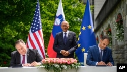 US Secretary of State Mike Pompeo, left, and Slovenia's Foreign Minister Anze Logar sign an agreement on fifth-generation internet technology as Slovenia's Prime Minister Janez Jansa stands at center, in Bled, Slovenia, Aug. 13, 2020.