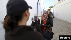 Cô Falconer Maroua (trái) chụp ảnh một người phụ nữ với chim ưng với mức giá vài dinar ở Sidi Bou Said, một địa điểm du lịch nổi tiếng gần Tunis, Tunisia, ngày 02/2/2016.