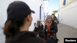 Falconer Maroua (à gauche) photographie une femme qui pose avec un faucon sur son épaule à Sidi Bou Said, une destination touristique populaire à proximité de Tunis, 2 février 2016.