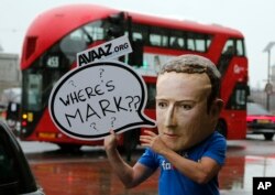 FILE - An activist wearing a Facebook CEO Mark Zuckerberg mask stands outside Portcullis House in Westminster as an international committee of parliamentarians met for a hearing on the impact of disinformation on democracy in London.