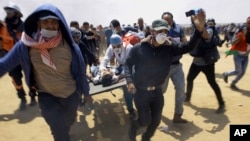 Palestinian medics and protesters evacuate a seriously wounded youth during a deadly protest at the Gaza Strip's border with Israel, east of Khan Younis, Gaza Strip, May 14, 2018. 