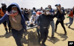 FILE - Palestinian medics and protesters evacuate a seriously wounded youth during a deadly protest at the Gaza Strip's border with Israel, east of Khan Younis, Gaza Strip, May 14, 2018.