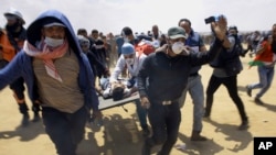FILE - Palestinian medics and protesters evacuate a seriously wounded youth during a deadly protest at the Gaza Strip's border with Israel, east of Khan Younis, Gaza Strip, May 14, 2018. 