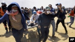 Abatabara ba Palestina hamwe n'abigaragamvya batwara abakomeretse ku karere ka Gaza kari ku rubibe na Isirayeli, itariki 14/05/2018. 