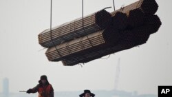在中国唐山曹妃甸港口，工人把钢管装船。（2012年2月20日）中国钢铁产品受到欧盟制裁